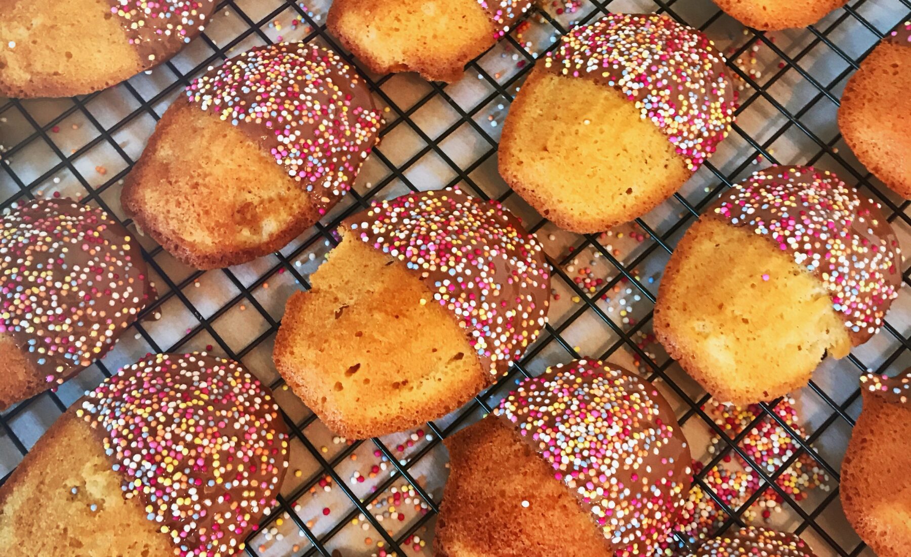 Madeleines dipped in chocolate dusted with 100s and 1000s